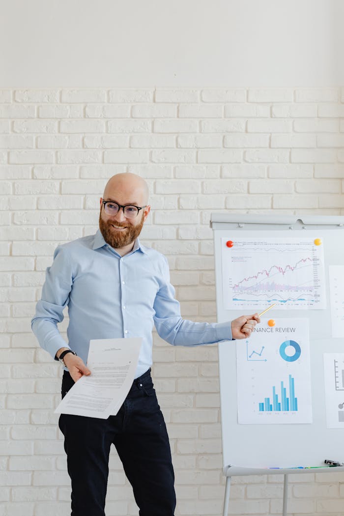 Smiling businessman with beard presenting financial charts at an office meeting.